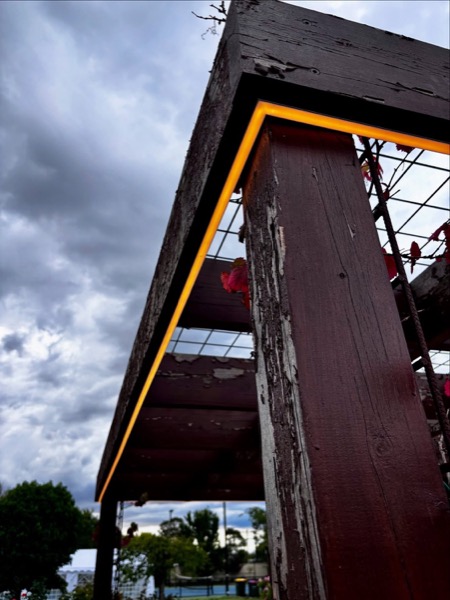A timber gable outlined in warm light against a stormy evening sky