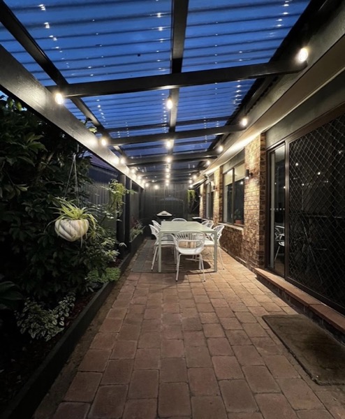 A covered brick walkway lit at dusk