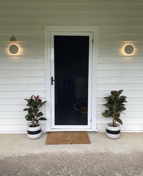 A front entry with a wall light on either side of the door