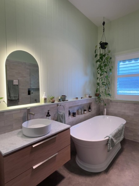 A bathroom vanity with a lit mirror above it