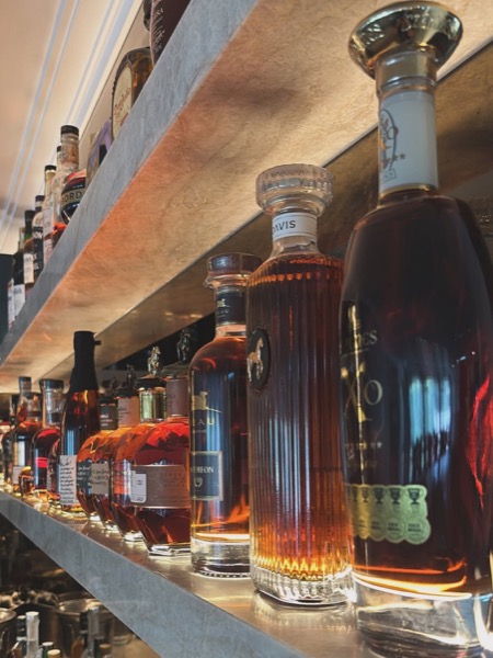 Lit shelving above a bar holding bottles and glassware