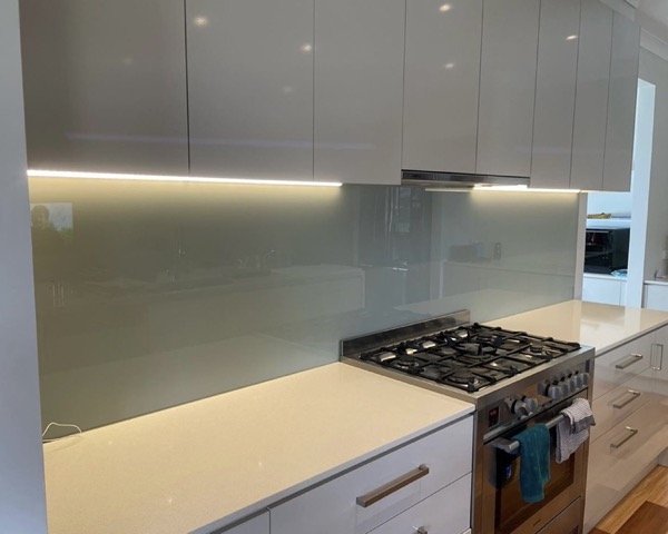 A kitchen with a lit splashback and under cabinet lighting