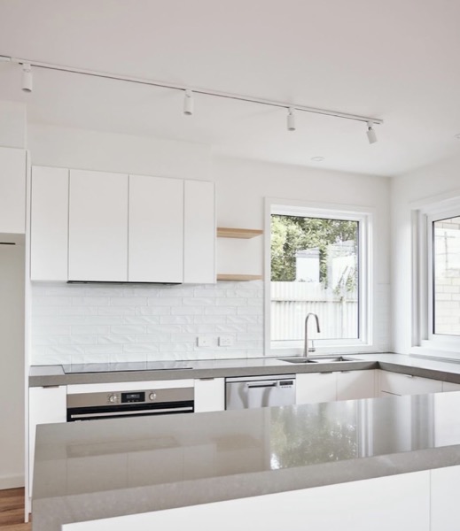 A kitchen with track lighting above the benches