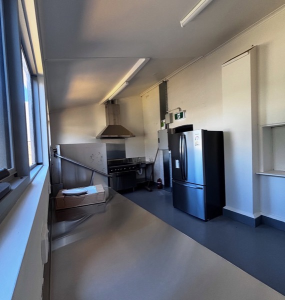 A kitchen with a rangehood and ceiling lighting
