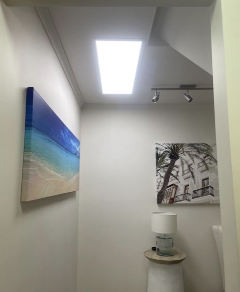 A hallway with a lit ceiling panel and track lights