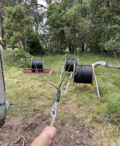 Cable drums set up on stands in bushland for an underground run