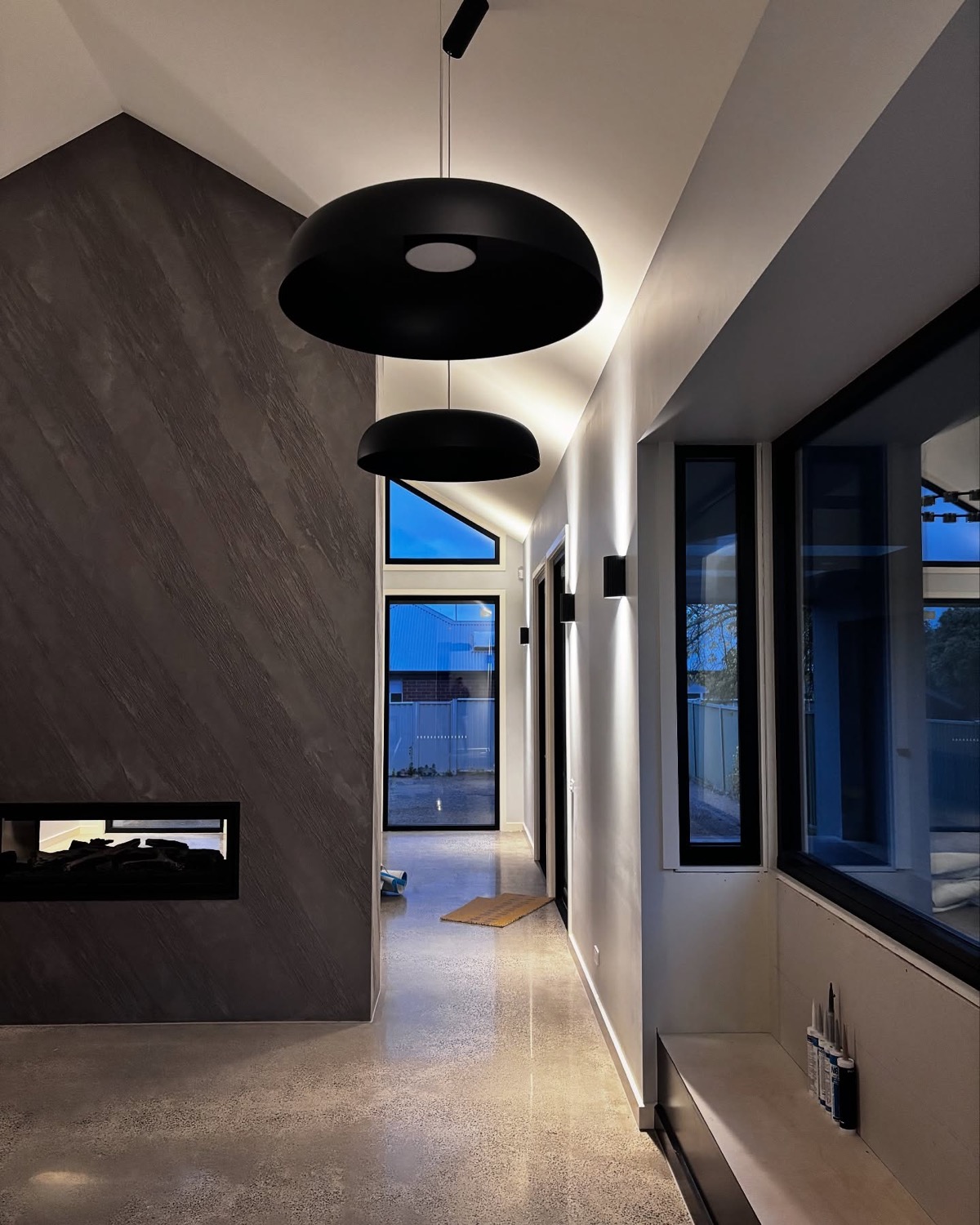 A hallway with two black pendant lights above a polished floor