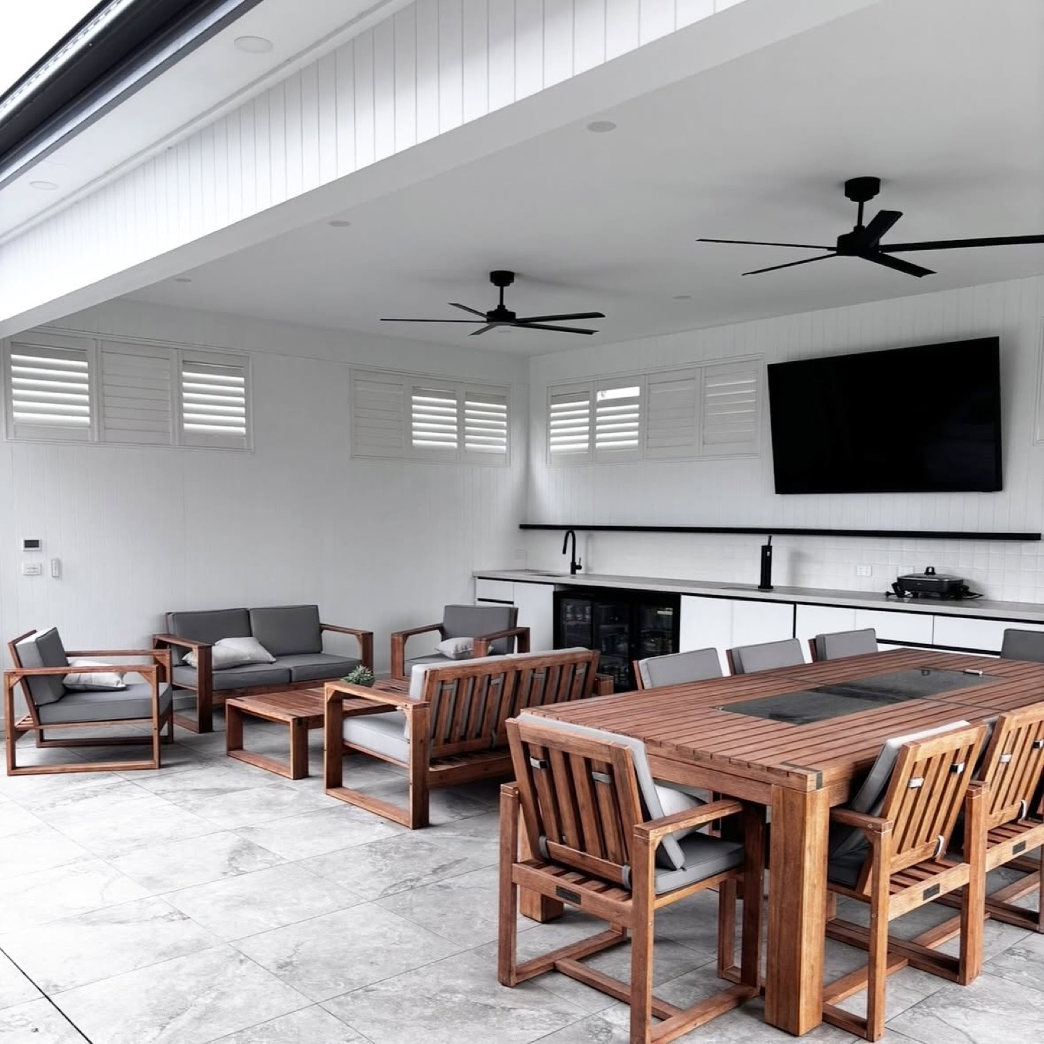 An outdoor entertaining area with black ceiling fans and downlights