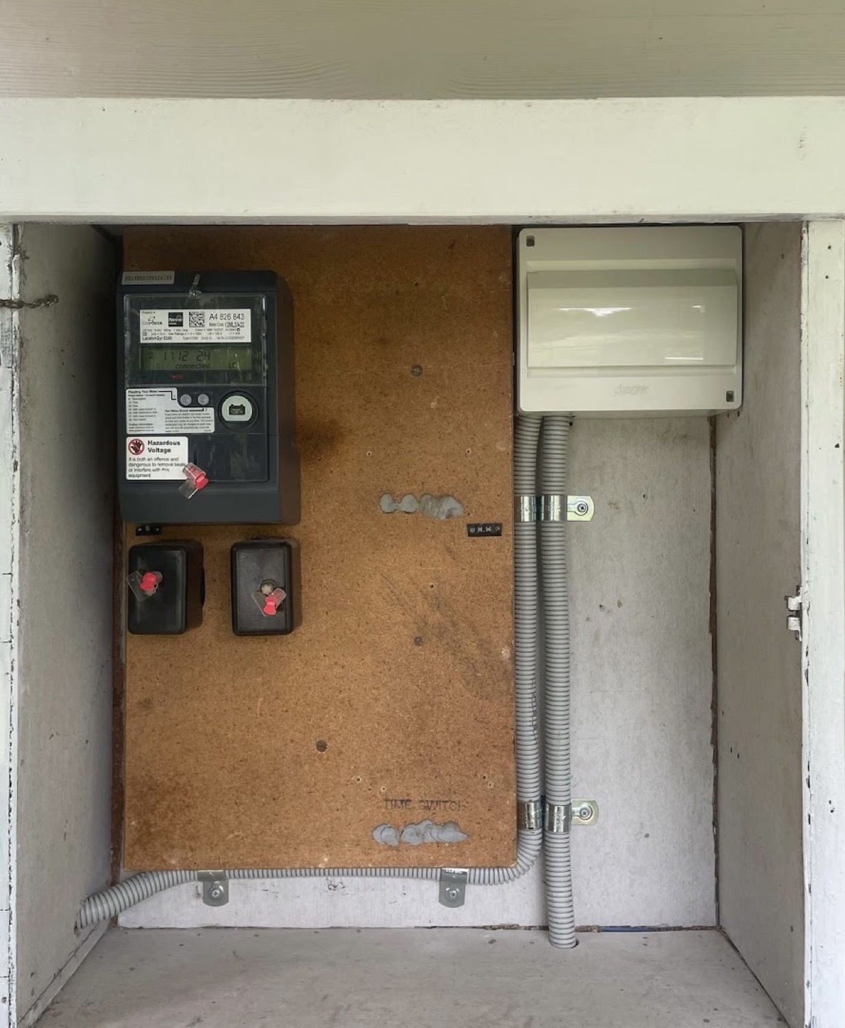 An open meter box with electricity meters mounted inside